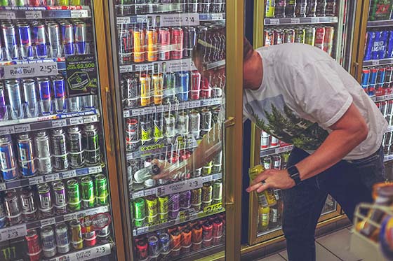 man grabbing a can of energy drink off the shelf